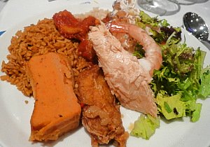 A sample of traditional African Food - Jollof rice served with moi-moi, shrimp and fish with salad.